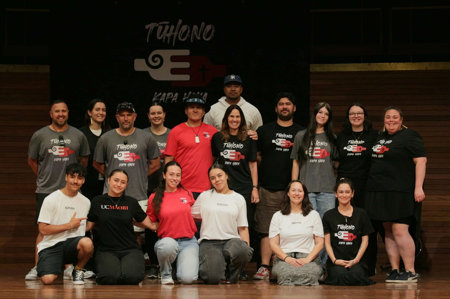 Group of people posing for a photo in front of a 'Tôhono Kapa Haka' banner.